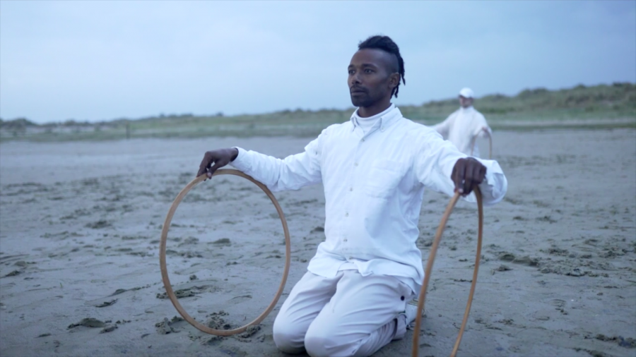 Christian Guerematchi in het zand met twee houten hoepels.