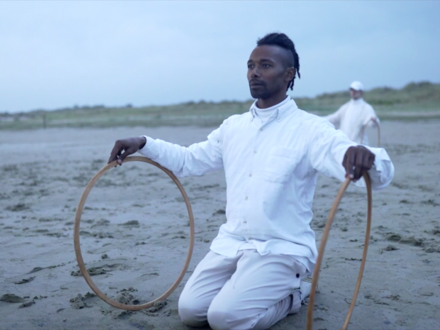 Christian Guerematchi in het zand met twee houten hoepels.